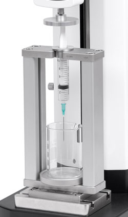 G1089 Syringe Compression Fixture is shown in a typical application mounted to a motorized test stand with optional eye end adapter.